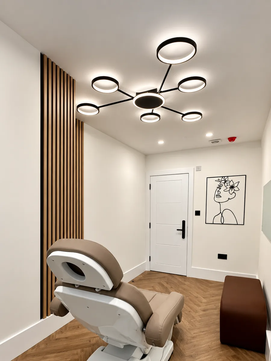 The Baker Street treatment room: a treatment chair under a ring-light fitting, beside a slatted oak wall